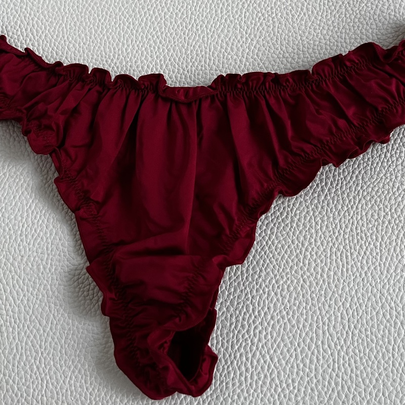 Kevyestä ja pehmeästi kierrätetystä polyamidisekoitteesta valmistetut string-malliset alushousut näyttävillä röyhelöreunoilla. Runsas poimutus vyötäröllä ja lahkeensuissa. Lindex,  Koko L