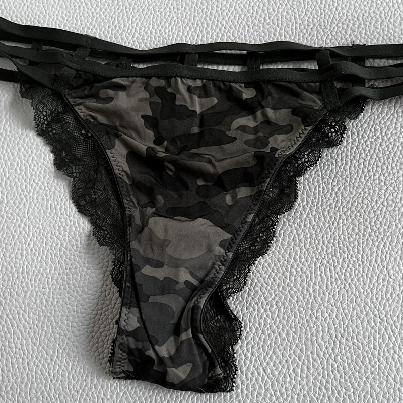 String-malliset alushousut pehmeästä, joustavasta kankaasta, jossa hillitty camo-kuvio edessä ja sivuilla leveät pitsireunat. Näyttävä moninauhainen vyötärö. 
Koko S.
