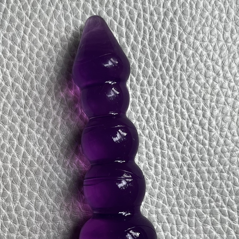 Käytetty ja puhdistettu helmimäinen violetti jelly-anustappi tukevalla turvapohjalla. 
Kokonaispituus 12 cm, käyttöpituus 11 cm, levein kohta läpimitta n. 2,7 cm.