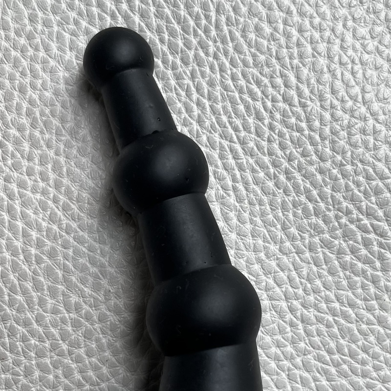 Käytetty ja puhdistettu. Musta käyrähkö  anaalitappi leveällä turvapohjalla. Kokonaispituus 10 cm, käyttöpituus 9 cm. Levein pallo läpimitta reilu 2 cm.